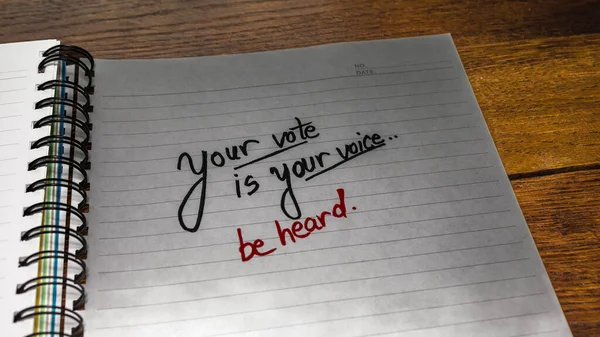 Your vote is your voice, handwriting  text on paper, political message. Political text on office agenda. Concept of democracy, voting, politics. Copy space.