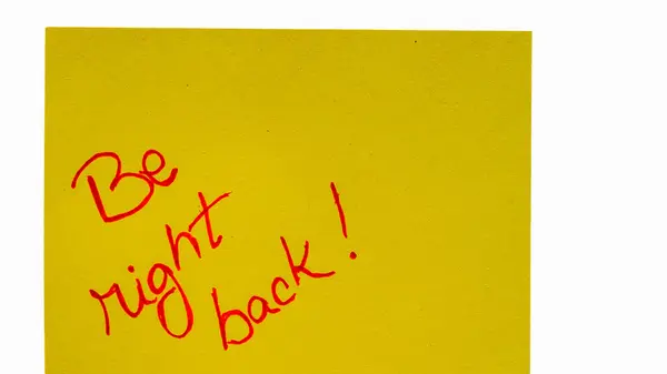 Be right back handwriting text close up isolated on orange paper with copy space. Writing text on memo post reminder