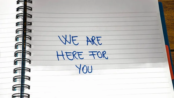We are here for you handwriting  text on paper, on office agenda. Copy space.