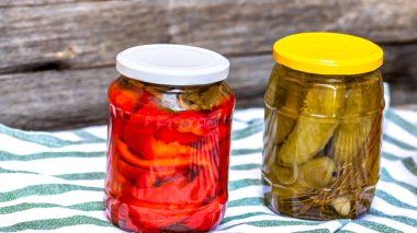 Kırmızı biber turşulu cam kavanozlar ve izole edilmiş salatalık turşusu. Çeşitli sebze turşulu kavanozlar. Kaba bir kompozisyonda yiyecek konseptini korudu.