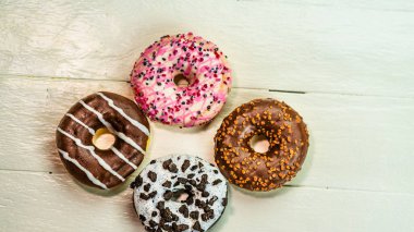 Beyaz ahşap masada renkli çörekler. Şekerli, şekerli, şekerli, şekerli, şekerli. Kopyalama alanı olan üst görünüm