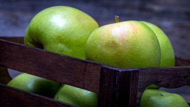 Tahta masada olgun yeşil elmalarla dolu tahta sandık..