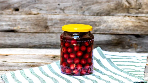 Glass jar with canned cherries fruits. Preserved fruits concept, canned fruits compote isolated in a rustic composition.