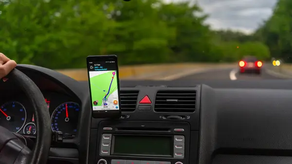 智能手机展示了 的地图 指出了穿过城市的路 司机使用Waze地图 免版税图库照片