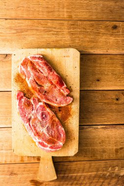 Ahşap bir masanın üzerindeki ahşap kesme tahtasına baharatlı domuz pirzolası. BBC için et, üst görüş, fotokopi alanı, barbekü konsepti.