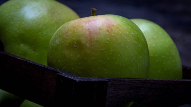 Tahta masada olgun yeşil elmalarla dolu tahta sandık..