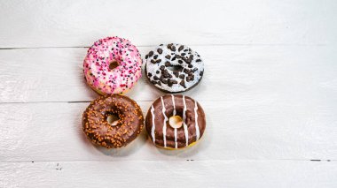 Beyaz ahşap masada renkli çörekler. Şekerli, şekerli, şekerli, şekerli, şekerli. Kopyalama alanı olan üst görünüm