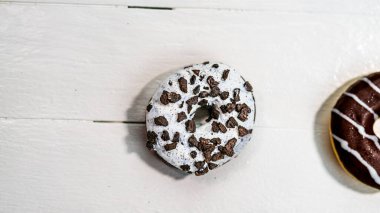 Beyaz ahşap masada renkli çörekler. Şekerli, şekerli, şekerli, şekerli, şekerli. Kopyalama alanı olan üst görünüm