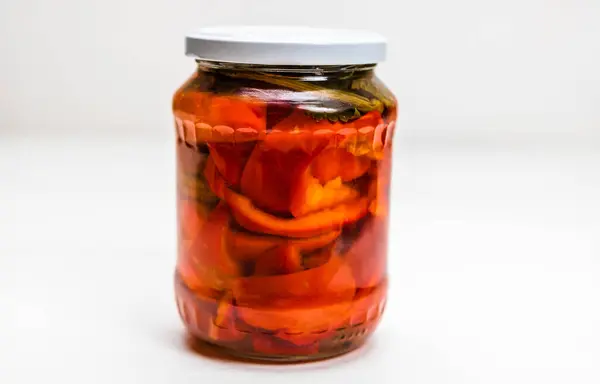 Glass jar with pickled red bell peppers isolated.