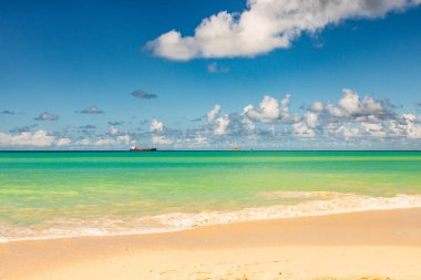 Beyaz kumlu Karayip plajı, derin mavi gökyüzü ve turkuaz su