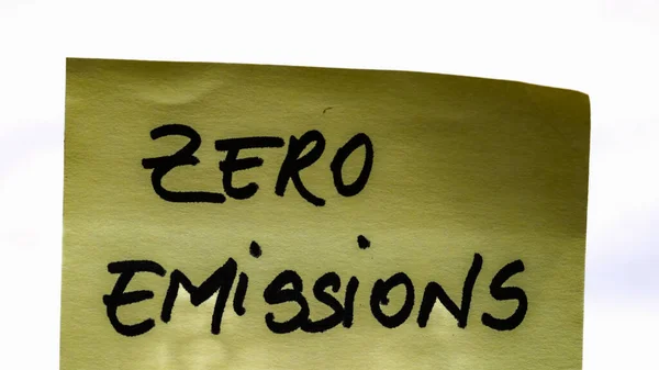 Zero emissions handwriting text close up isolated on yellow paper with copy space.