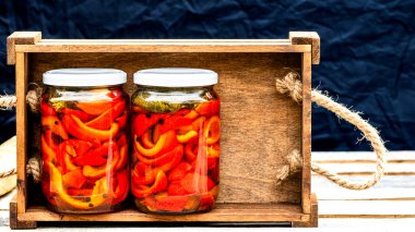 Cam kavanozlu tahta sandık, turşulu kırmızı çan biberi. Konserve gıda konsepti, yalıtılmış konserve sebzeler..