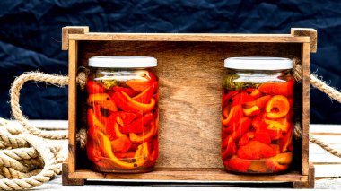 Cam kavanozlu tahta sandık, turşulu kırmızı çan biberi. Konserve gıda konsepti, yalıtılmış konserve sebzeler..