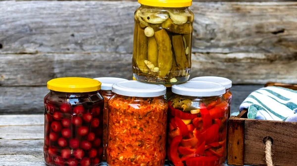 Jars with variety of canned vegetables and fruits, jars with zacusca. Preserved food concept in a rustic composition.