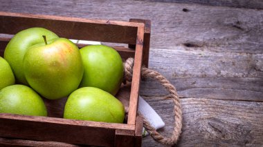 Tahta masada olgun yeşil elmalarla dolu tahta sandık..