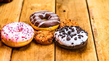Ahşap masada renkli çörekler. Jöleli şekerli tatlı yiyecekler, çikolatalı donutlar. Kopyalama alanı olan üst görünüm