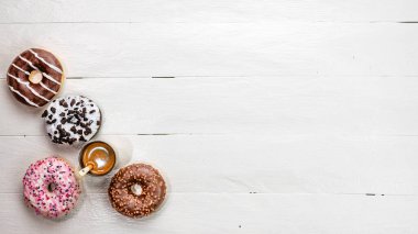 Beyaz ahşap masada renkli çörekler. Şekerli, şekerli, şekerli, şekerli, şekerli. Kopyalama alanı olan üst görünüm