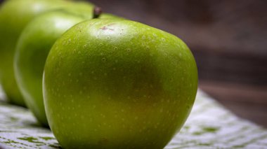 Ahşap masadaki olgun yeşil elmaların ayrıntıları.