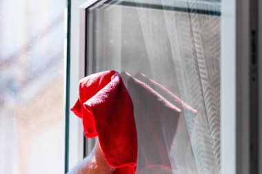 Kırmızı mikrofiber halı kullanarak cam silen bir adam, temizlik hizmeti kavramı. Ev işleri ve ev idaresi kavramı