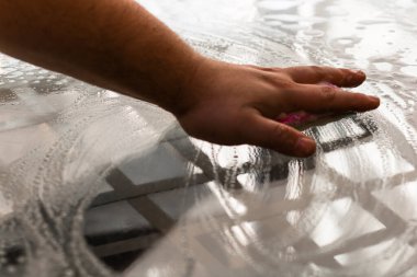 Sünger ve temizlik spreyi kullanarak cam masayı temizleyen adam, temizlik hizmeti konsepti. Ev işleri ve ev idaresi kavramı