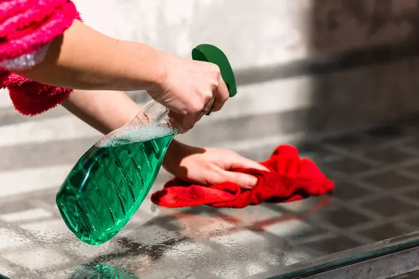 stock image Woman cleaning glass table red microfiber rug and cleaning sprayer, cleaning services concept. Housework and housekeeping concept