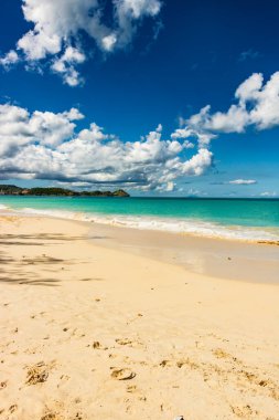 Beyaz kumlu Karayip plajı, derin mavi gökyüzü ve turkuaz su