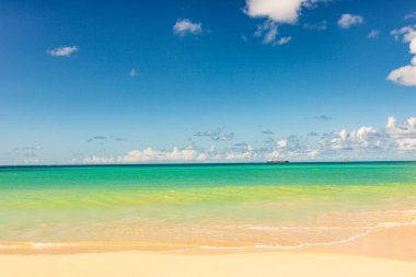 Beyaz kumlu Karayip plajı, derin mavi gökyüzü ve turkuaz su