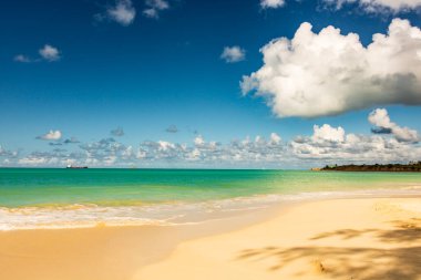 Beyaz kumlu Karayip plajı, derin mavi gökyüzü ve turkuaz su