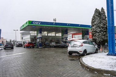 Bir OMV benzin istasyonunun dışı. Benzin pompaları ve arabalar kar yağarken yakıt ikmali yapıyorlar.
