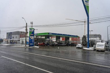 Bir OMV benzin istasyonunun dışı. Benzin pompaları ve arabalar kar yağarken yakıt ikmali yapıyorlar.