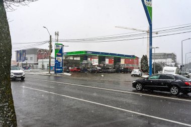 Bir OMV benzin istasyonunun dışı. Benzin pompaları ve arabalar kar yağarken yakıt ikmali yapıyorlar.