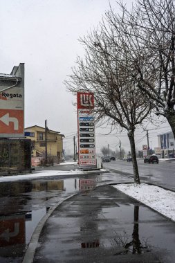 LUKOIL benzin istasyonunun dışı. Benzin pompaları ve arabalar kar yağarken yakıt ikmali yapıyorlar.