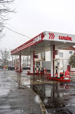 LUKOIL benzin istasyonunun dışı. Benzin pompaları ve arabalar kar yağarken yakıt ikmali yapıyorlar.