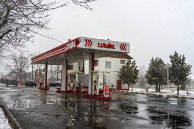 LUKOIL benzin istasyonunun dışı. Benzin pompaları ve arabalar kar yağarken yakıt ikmali yapıyorlar.