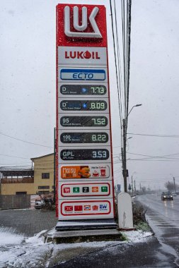 LUKOIL benzin istasyonunun dışı. Benzin pompaları ve arabalar kar yağarken yakıt ikmali yapıyorlar.