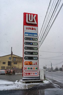 LUKOIL benzin istasyonunun dışı. Benzin pompaları ve arabalar kar yağarken yakıt ikmali yapıyorlar.