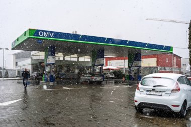 Bir OMV benzin istasyonunun dışı. Benzin pompaları ve arabalar kar yağarken yakıt ikmali yapıyorlar.