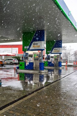 Bir OMV benzin istasyonunun dışı. Benzin pompaları ve arabalar kar yağarken yakıt ikmali yapıyorlar.