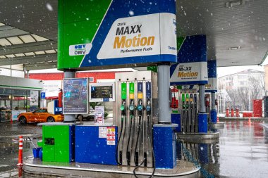Bir OMV benzin istasyonunun dışı. Benzin pompaları ve arabalar kar yağarken yakıt ikmali yapıyorlar.