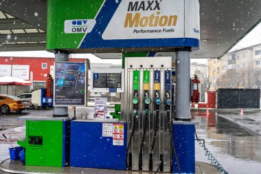 Bir OMV benzin istasyonunun dışı. Benzin pompaları ve arabalar kar yağarken yakıt ikmali yapıyorlar.