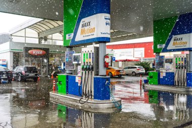 Bir OMV benzin istasyonunun dışı. Benzin pompaları ve arabalar kar yağarken yakıt ikmali yapıyorlar.