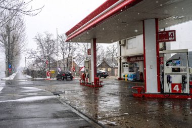 LUKOIL benzin istasyonunun dışı. Benzin pompaları ve arabalar kar yağarken yakıt ikmali yapıyorlar.