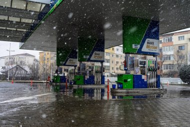Bir OMV benzin istasyonunun dışı. Benzin pompaları ve arabalar kar yağarken yakıt ikmali yapıyorlar.