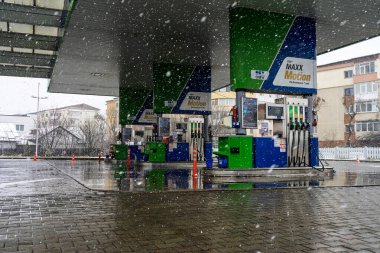 Bir OMV benzin istasyonunun dışı. Benzin pompaları ve arabalar kar yağarken yakıt ikmali yapıyorlar.