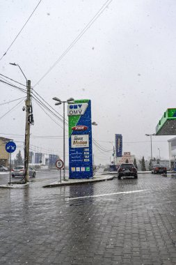 Bir OMV benzin istasyonunun dışı. Benzin pompaları ve arabalar kar yağarken yakıt ikmali yapıyorlar.