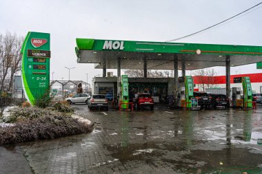 Bir MOL benzin istasyonunun dışı. Benzin pompaları ve arabalar kar yağarken yakıt ikmali yapıyorlar.