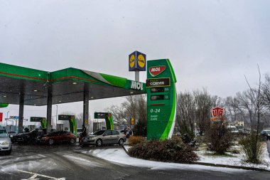 Bir MOL benzin istasyonunun dışı. Benzin pompaları ve arabalar kar yağarken yakıt ikmali yapıyorlar.