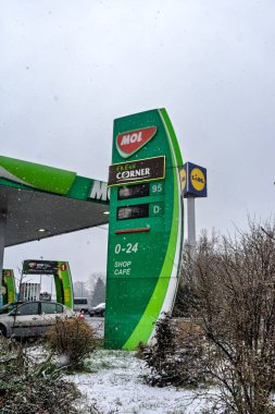 Bir MOL benzin istasyonunun dışı. Benzin pompaları ve arabalar kar yağarken yakıt ikmali yapıyorlar.