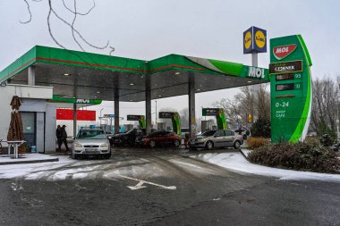 Bir MOL benzin istasyonunun dışı. Benzin pompaları ve arabalar kar yağarken yakıt ikmali yapıyorlar.