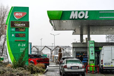 Bir MOL benzin istasyonunun dışı. Benzin pompaları ve arabalar kar yağarken yakıt ikmali yapıyorlar.